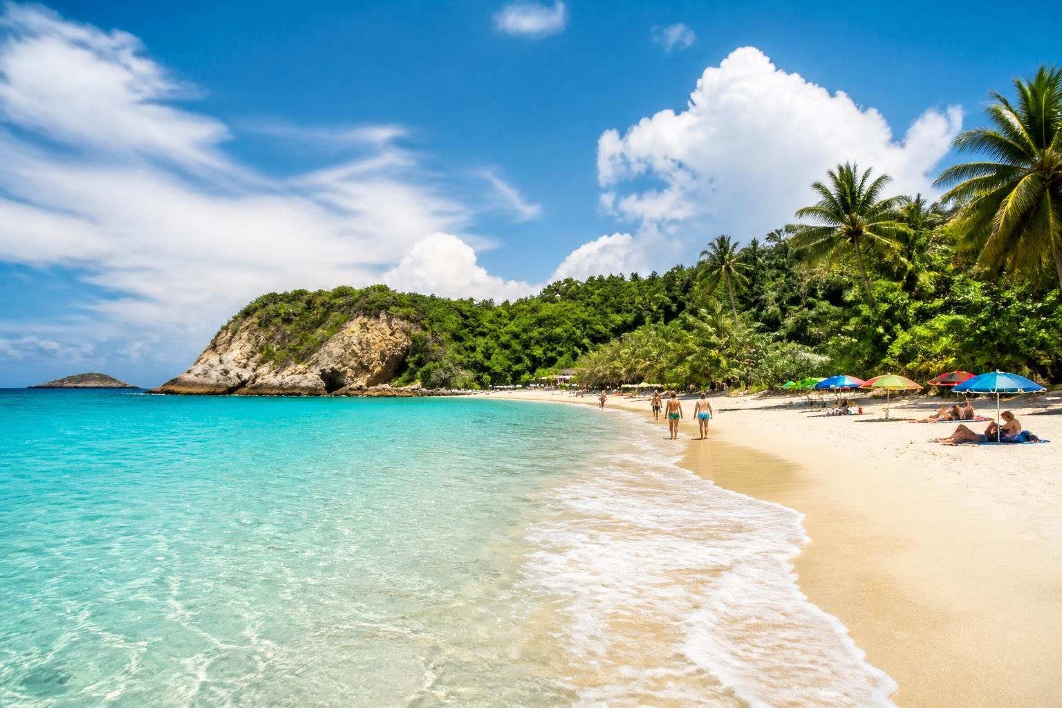 Praia de Lagoinha com areia branca, água azul cristalina, coqueiros e algumas pessoas aproveitando o dia ensolarado.